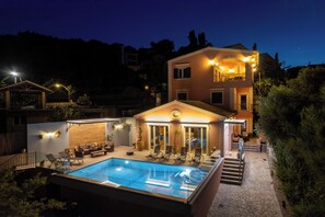 A two-story building with a swimming pool, outdoor seating, and a staircase leading to the upper floor.
