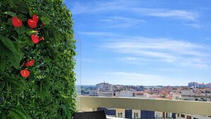 A balcony with a table set for two, a chair, and a green plant with red flowers. - Furnished Studio 2** - On the edge of the Grande Plage - Swimming pool - Terrace (Biarritz)
