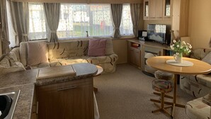 Un intérieur de camping-car confortable avec un canapé, une table à manger, un coin cuisine et un téléviseur.