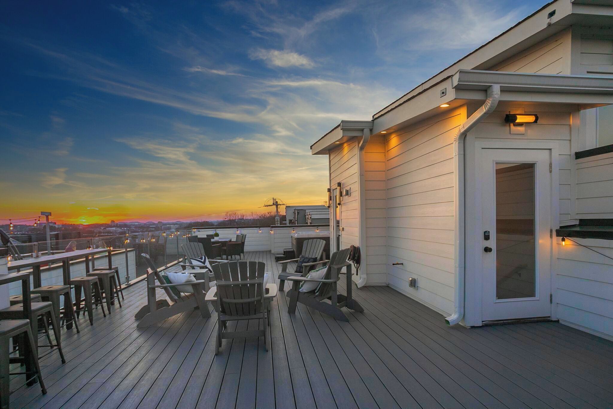 A deck with outdoor seating and a view of the sunset.