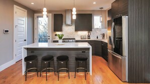 A modern kitchen with a central island, bar stools, stainless steel appliances, and pendant lighting. - ROOFTOP HOT TUB- FIRE PIT- MASSIVE CITY VIEWS (Nashville)
