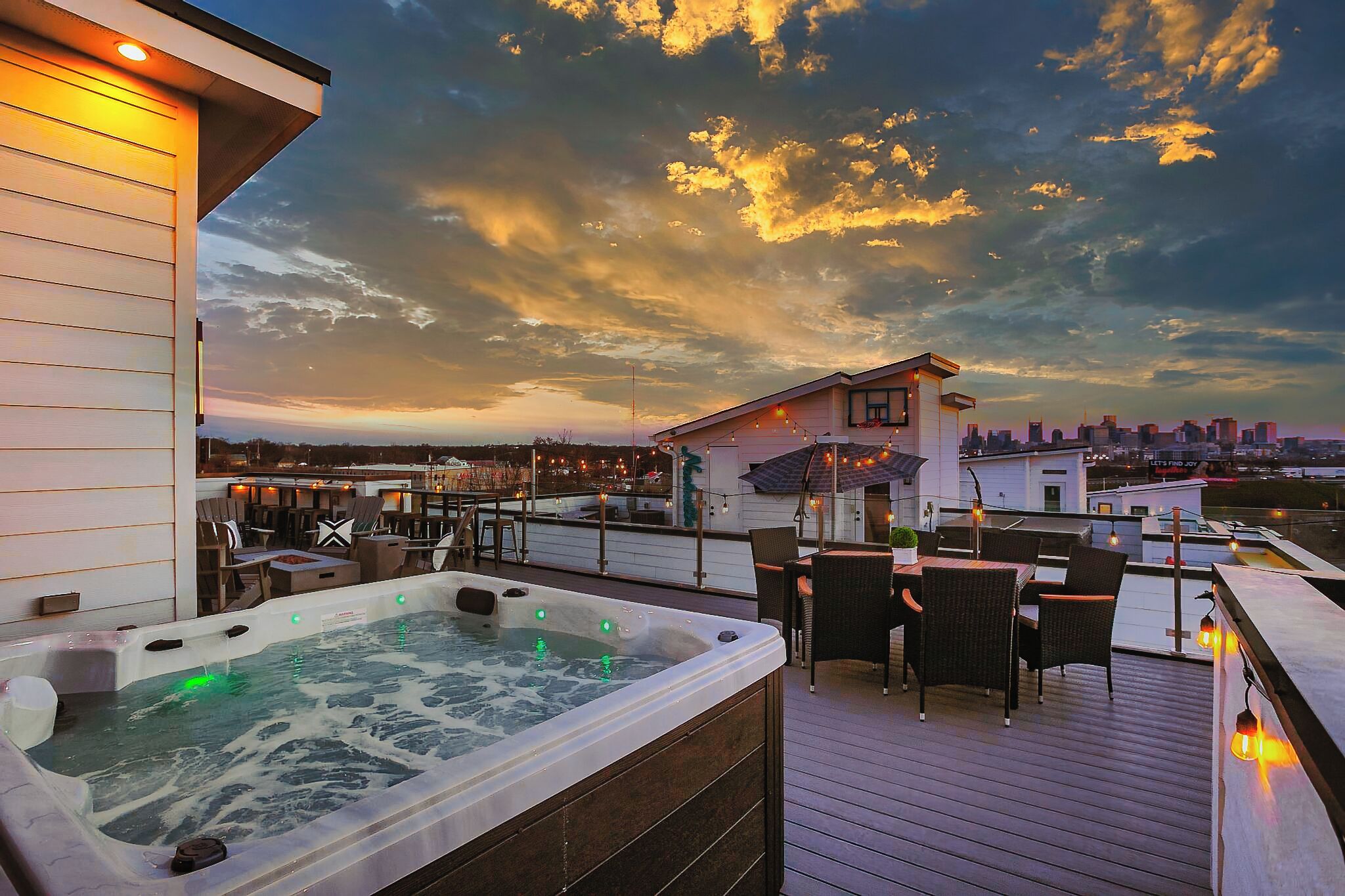A rooftop terrace with a hot tub, outdoor seating, and a city skyline view.