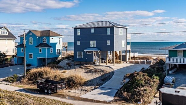 Une zone résidentielle côtière avec des maisons, une plage et un ciel dégagé.