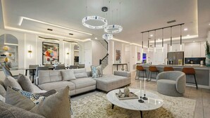 Ein modernes Wohnzimmer mit einer Eckcouch, einem runden Couchtisch und einem Essbereich mit Bar.
