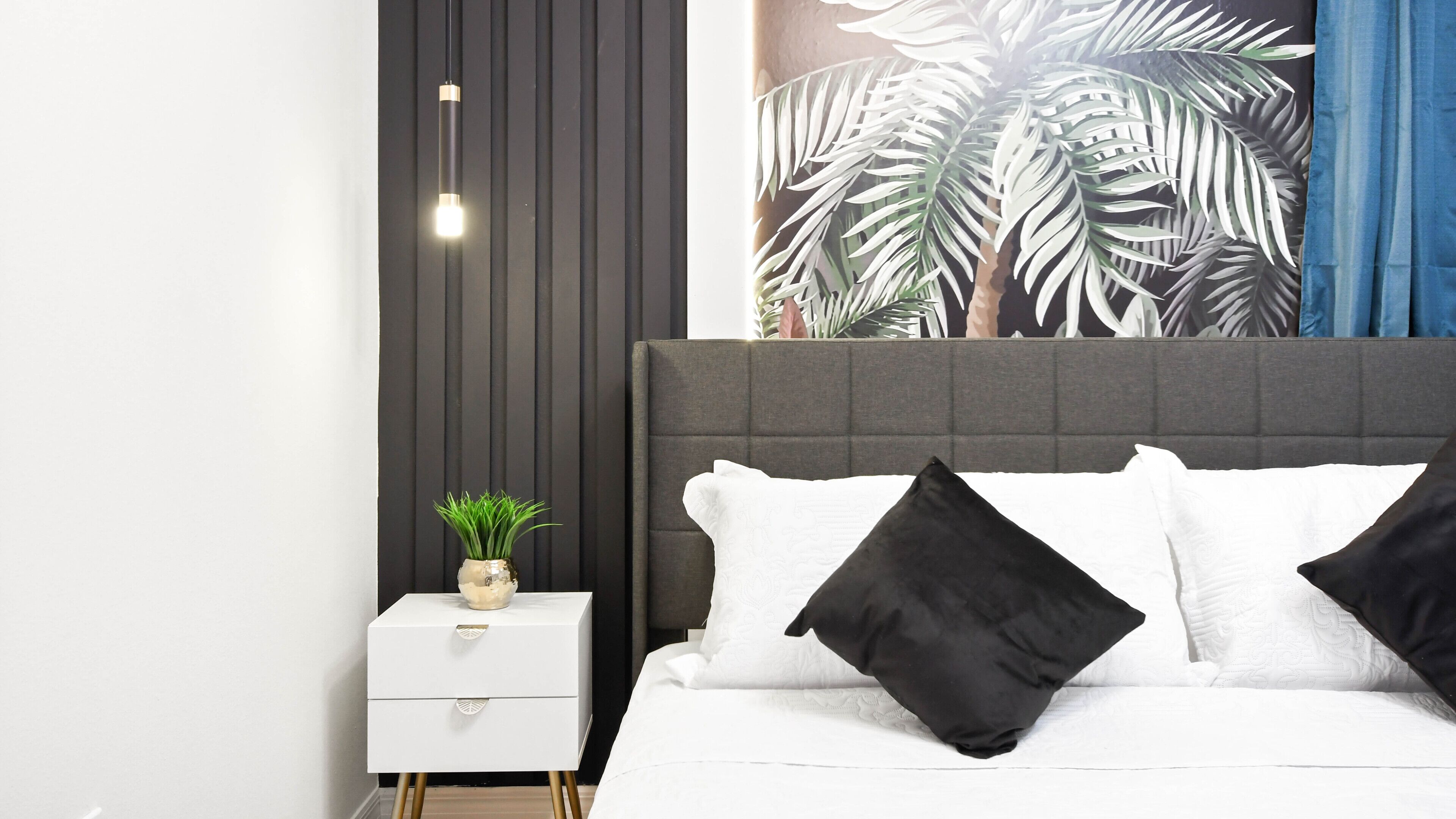 Un dormitorio moderno con una cama, una mesita de noche blanca y una lámpara de pared.