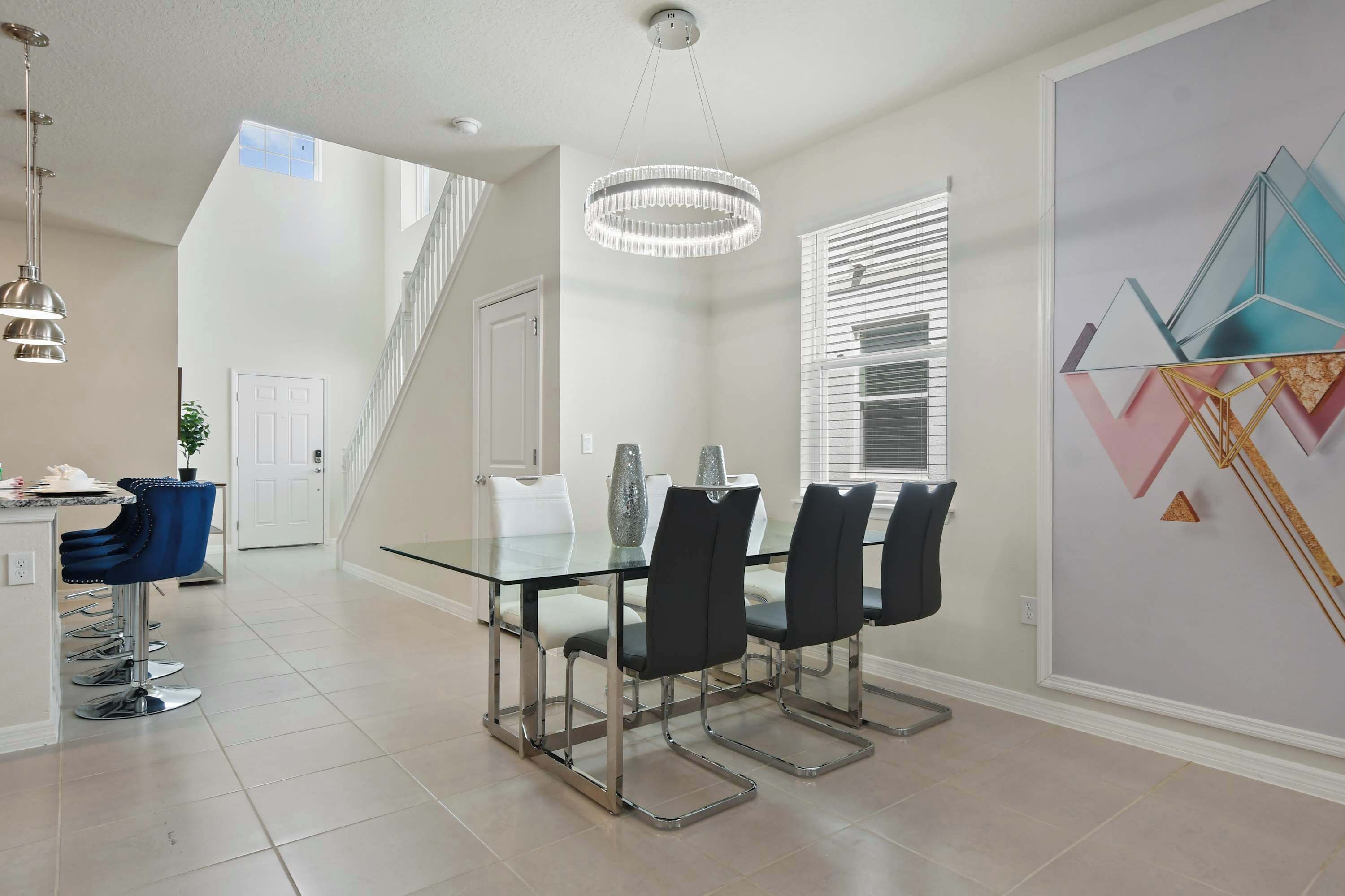 A modern dining area with a glass table, black chairs, and a chandelier.