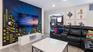 Una sala de estar moderna con un televisor de pantalla plana grande, un sofá de cuero negro y una mesa de centro de mármol.