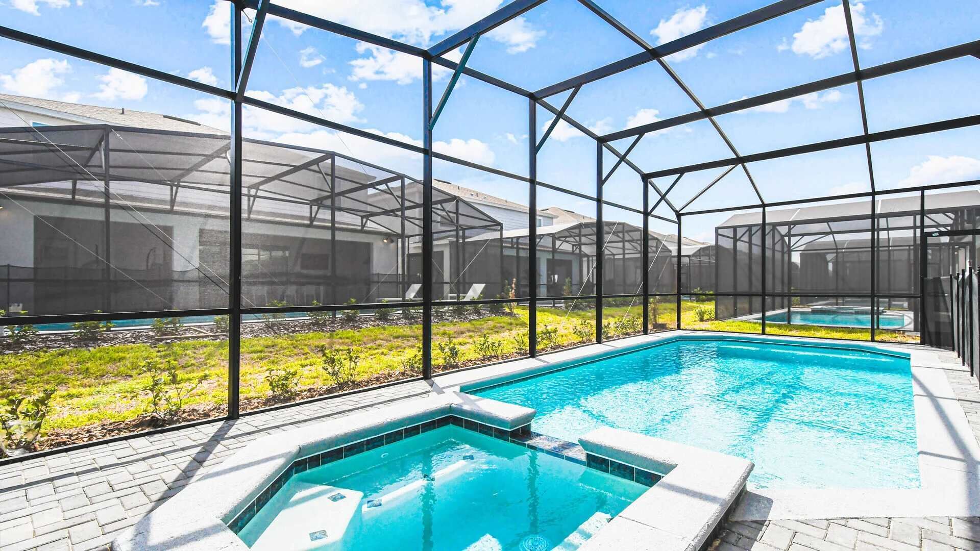 Una piscina con cerramiento de vidrio, rodeada por un jardín y una estructura de invernadero.
