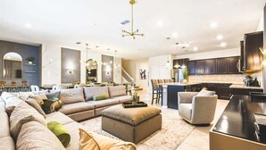 Een moderne woonkamer met een hoekbank, een poef en een eethoek met stoelen.