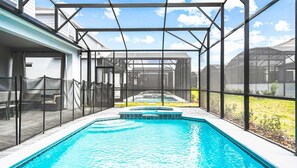 En indendørs swimmingpool med et glasoverdækket område, omgivet af et hegn og en overdækket terrasse.