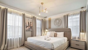 Een moderne slaapkamer met een groot bed, nachtkastjes en een plafondlamp.