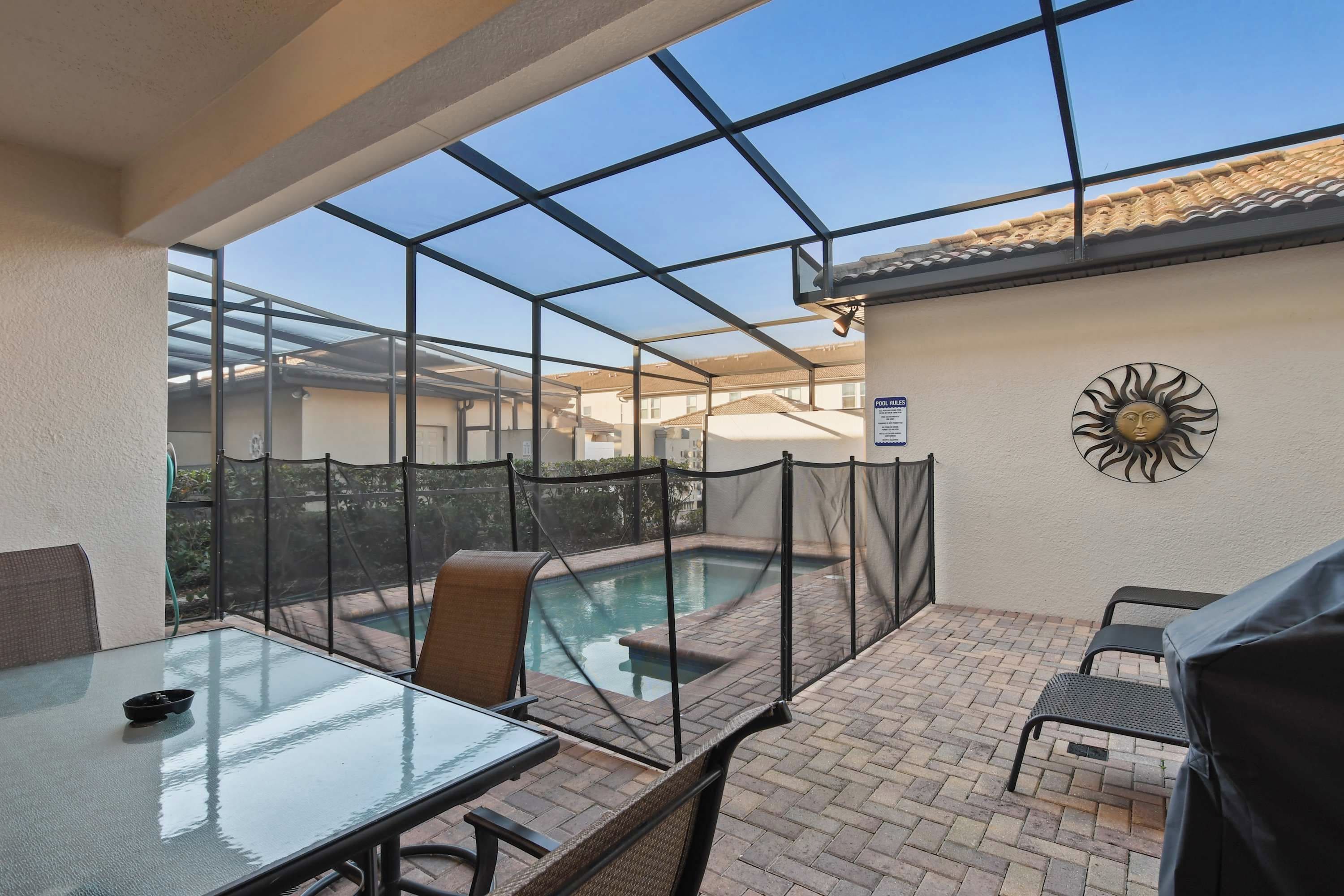 Área externa coberta com piscina, mesa de vidro, cadeiras e um alpendre.