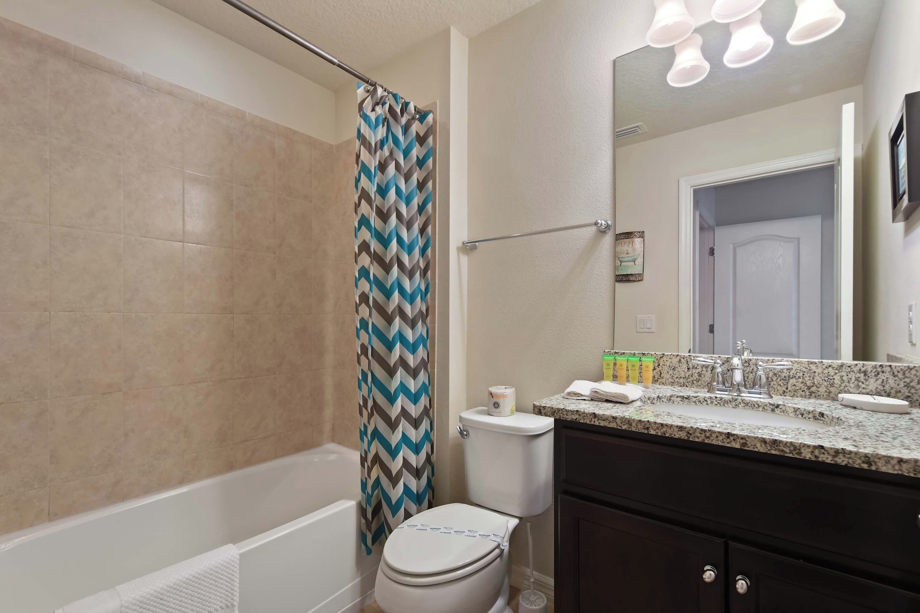 A bathroom with a shower, toilet, and vanity with a sink and mirror.