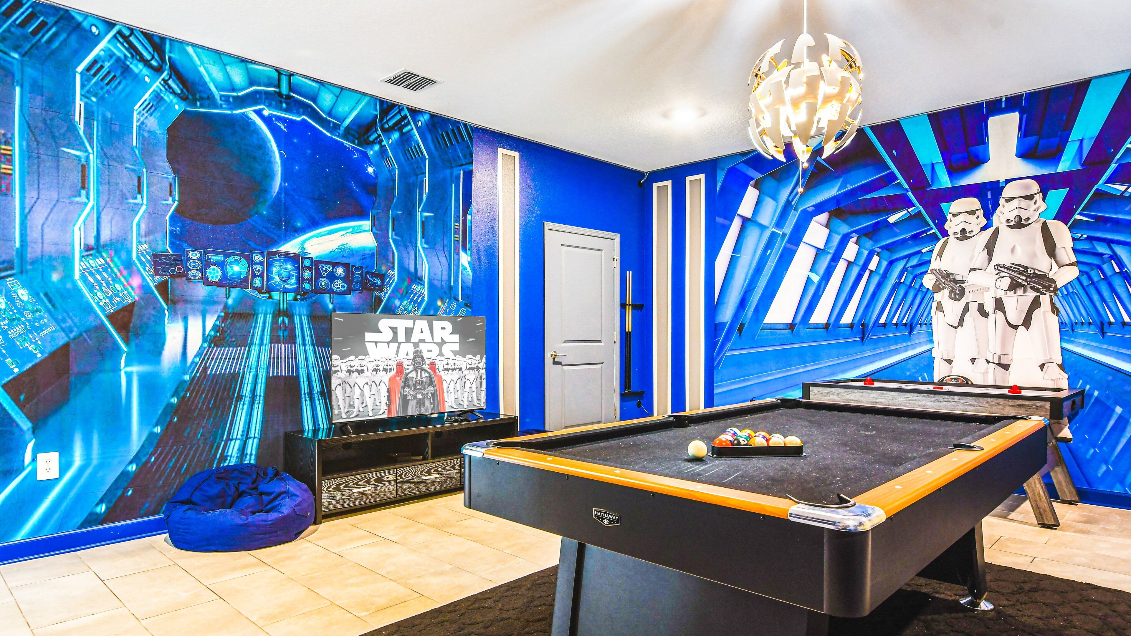 Ein Zimmer mit Billardtisch, Star Wars Dekoration und einer blau gestalteten Wand.