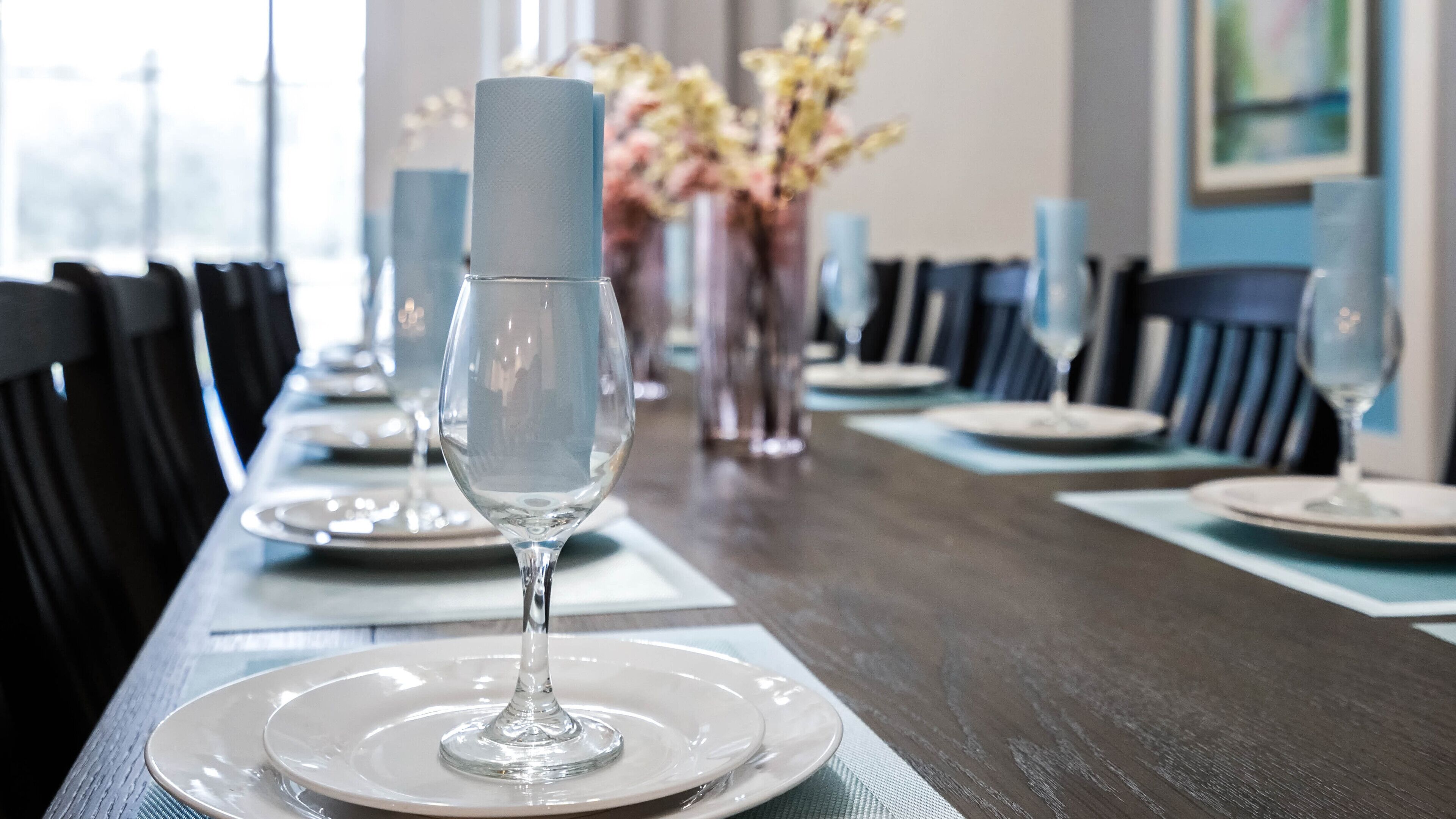 Une table à manger dressée avec des assiettes, des verres et un centre de table.