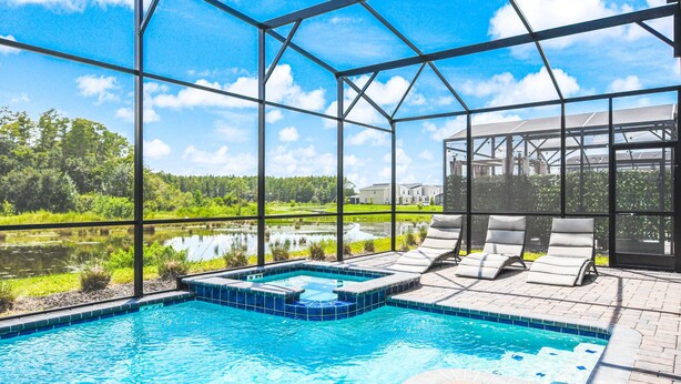 A swimming pool with a hot tub, lounge chairs, and a view of a lake and greenery. - Storey Lake Resort 9br Cozy Home With Theater 2965 (Kissimmee)