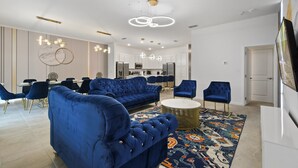 A modern living room with a blue sofa, a round coffee table, and a patterned rug. - Family-friendly Luxury Home Near Disney & More (Kissimmee)