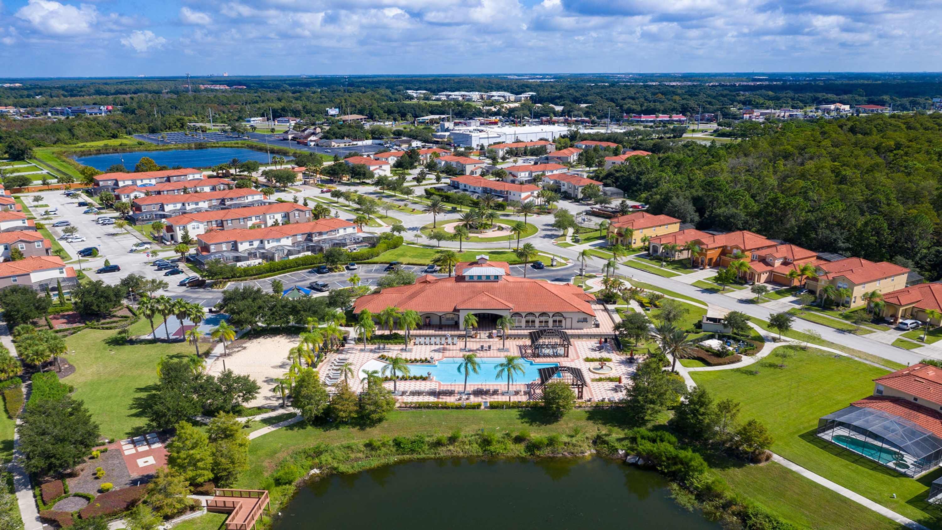 A residential area with multiple houses, a swimming pool, and a large building with a red roof.