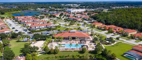 A residential area with multiple houses, a swimming pool, and a large building with a red roof.