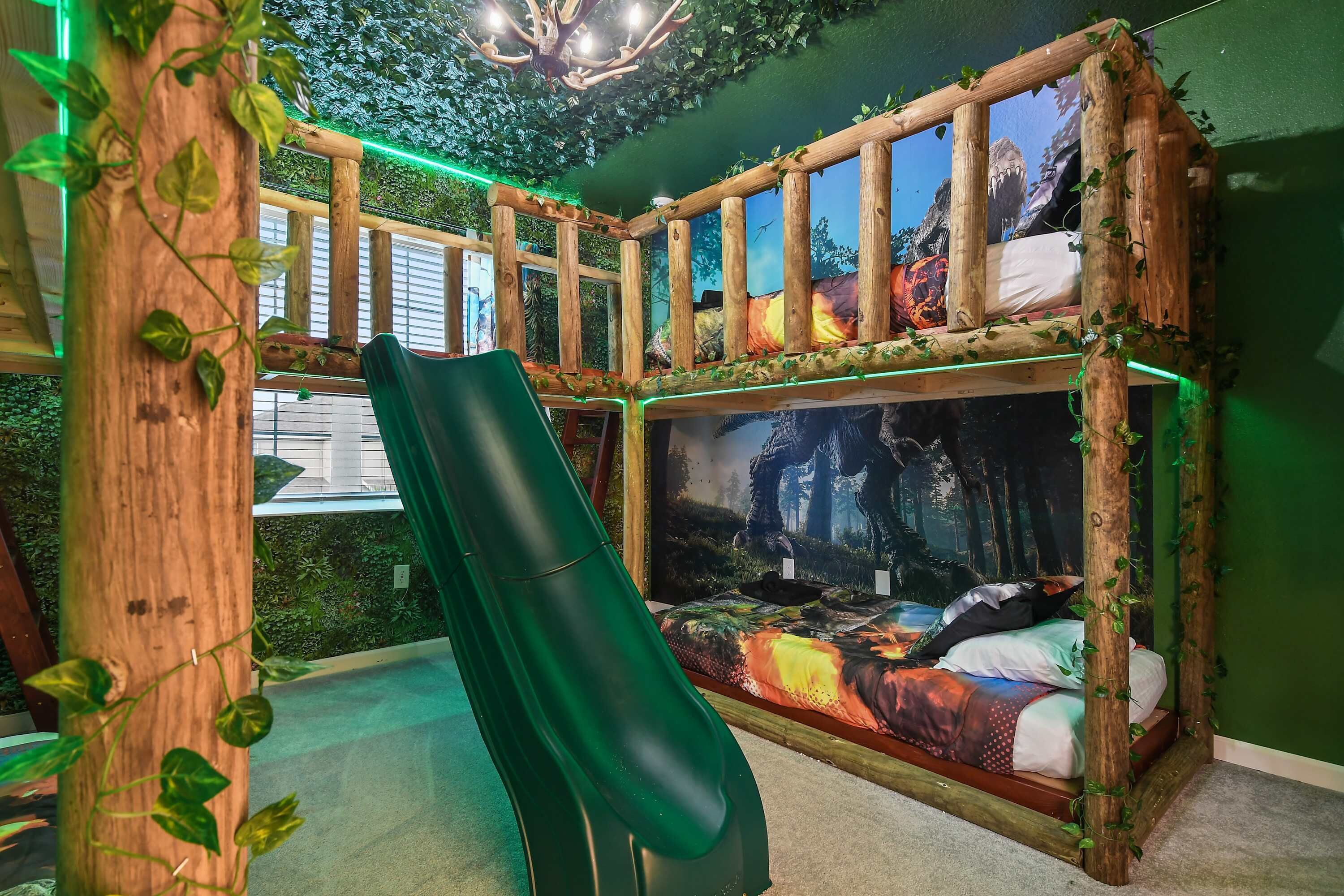 A room with a slide, a bed with a forest-themed mural, and green walls.