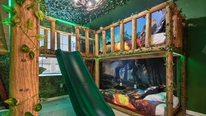 A room with a slide, a bed with a forest-themed mural, and green walls. - Family-friendly Luxury Home Near Disney & More (Kissimmee)