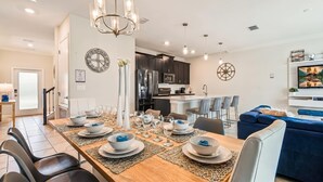 A modern kitchen with dark cabinets, a stainless steel refrigerator, and a microwave. - 4BR Retreat in Champions Gate w/ Private Pool (Davenport)