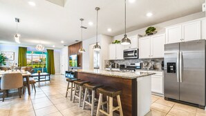 A modern kitchen with a central island, stainless steel appliances, and pendant lighting. - 7BR Lake View Villa Pool Spa - Solterra Resort (Davenport)