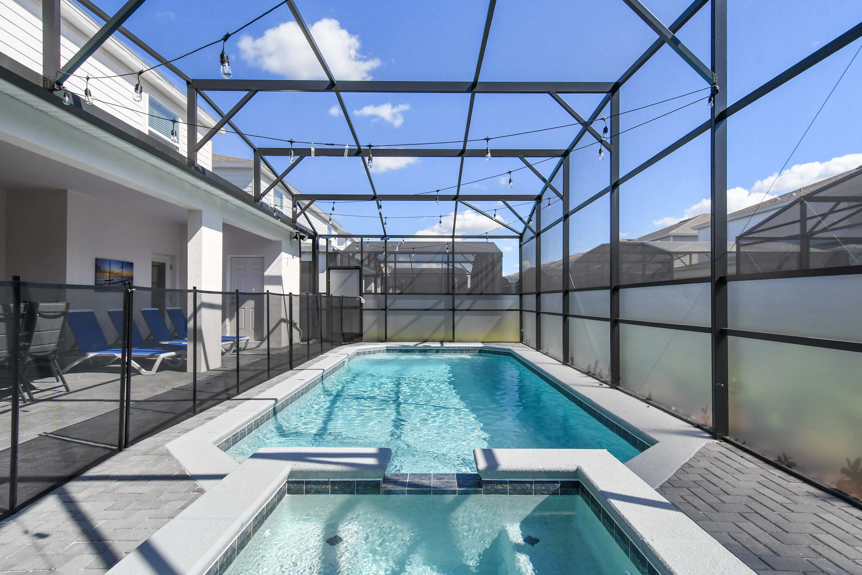 Piscina interior com cobertura de vidro, rodeada por espreguiçadeiras e um espaço de terraço.