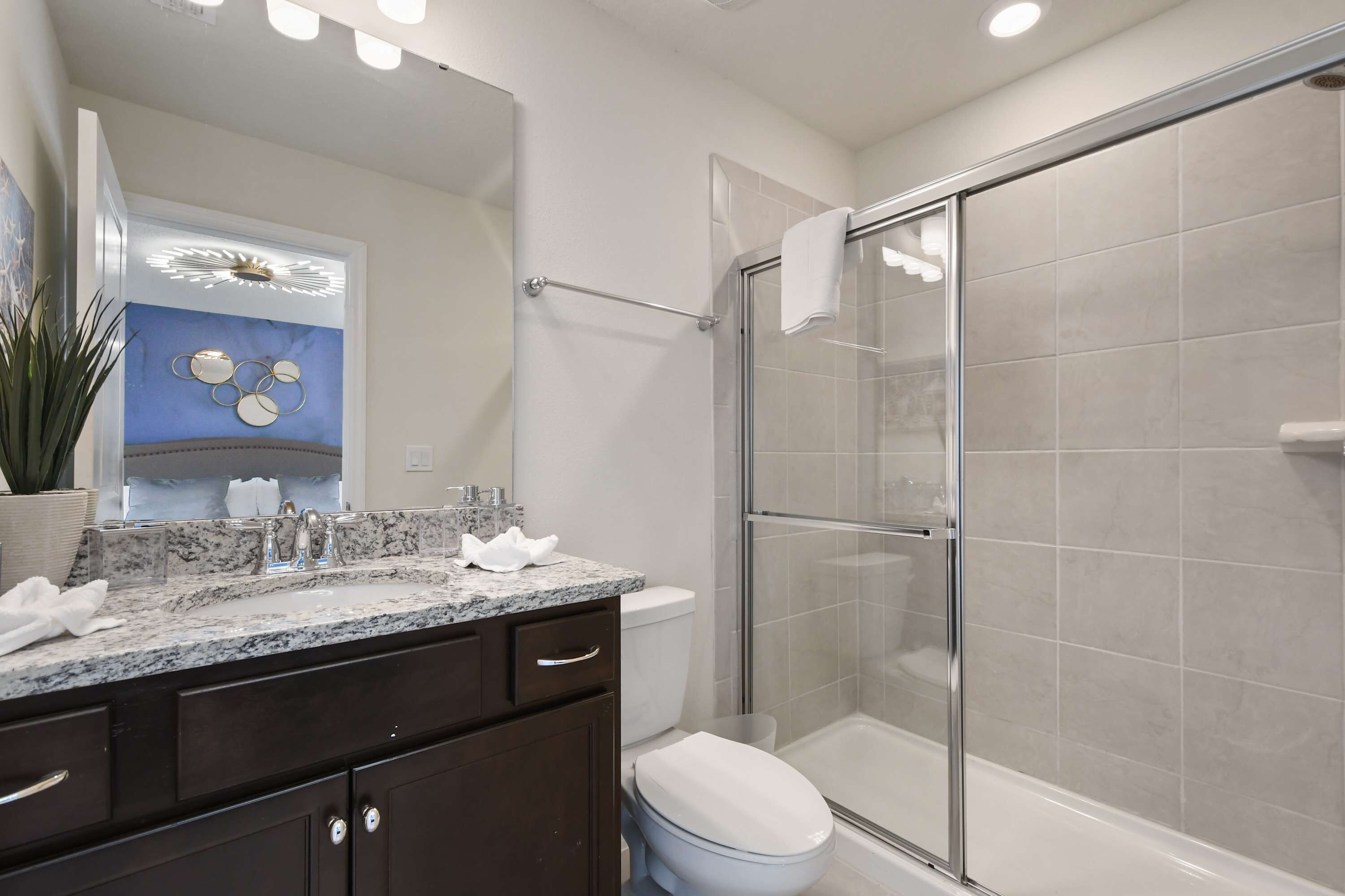 A modern bathroom with a glass-enclosed shower, a marble countertop, and a white toilet.
