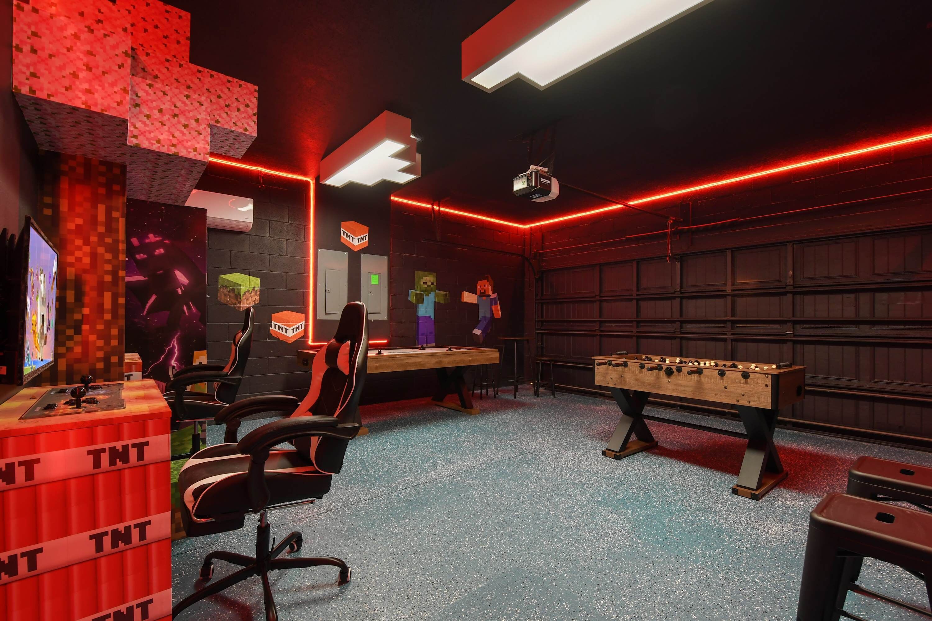 A room with a foosball table, a gaming chair, and a desk with a computer monitor.