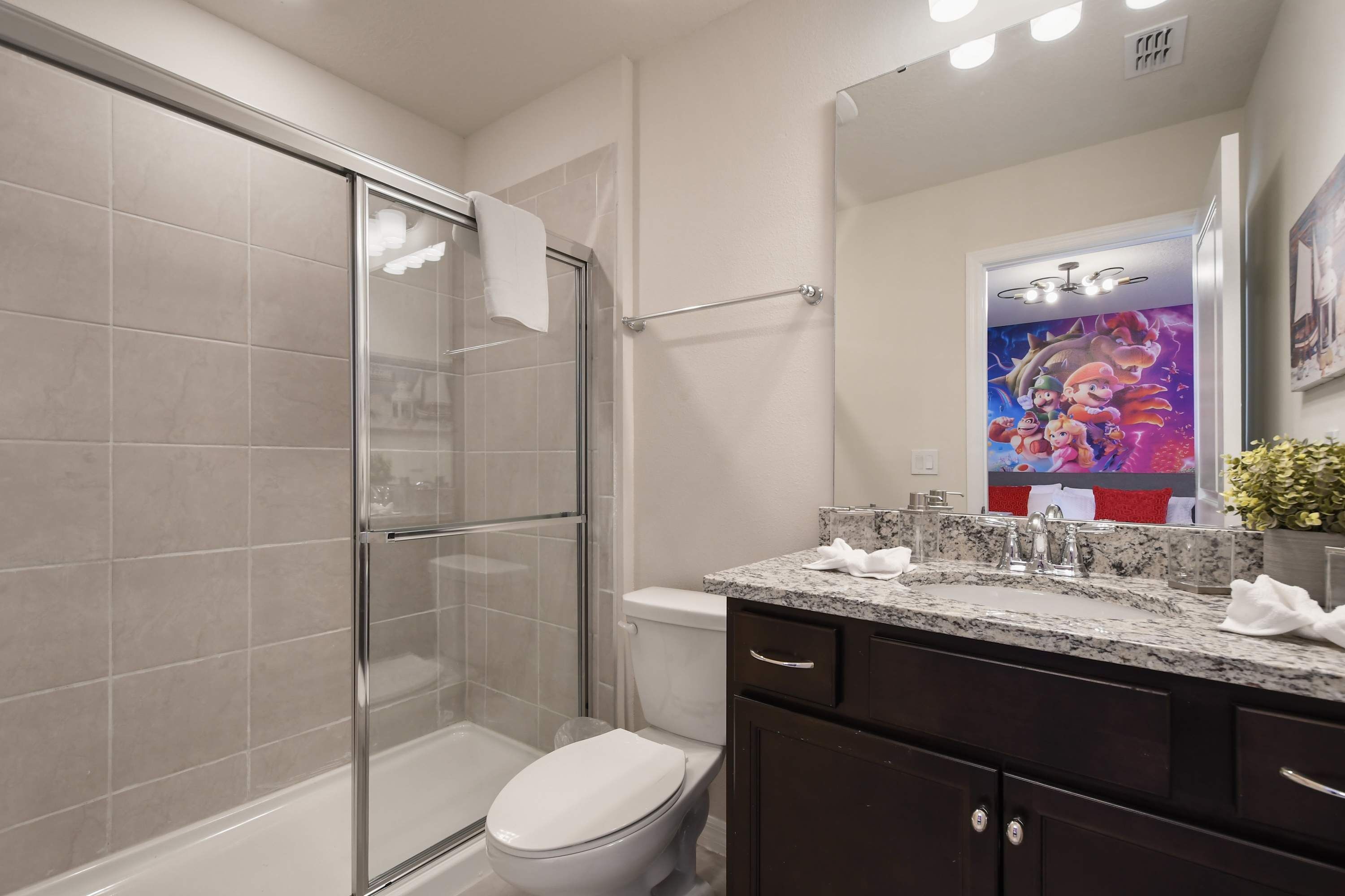 A modern bathroom with a glass shower enclosure, a white toilet, and a granite countertop with a sink.