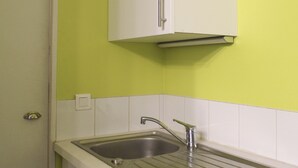 A kitchen with a sink, white cabinets, and a green wall. - Colorful 1BR in Beaugrenelle - 5min to Metro (Paris)