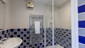 Een badkamer met een wit wastafelmeubel, een douchecabine van glas en blauwe betegelde wanden.