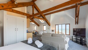 Ruime kamer met een groot bed, een sofa en een bureau. Er zijn dakramen en uitzicht op de omgeving.