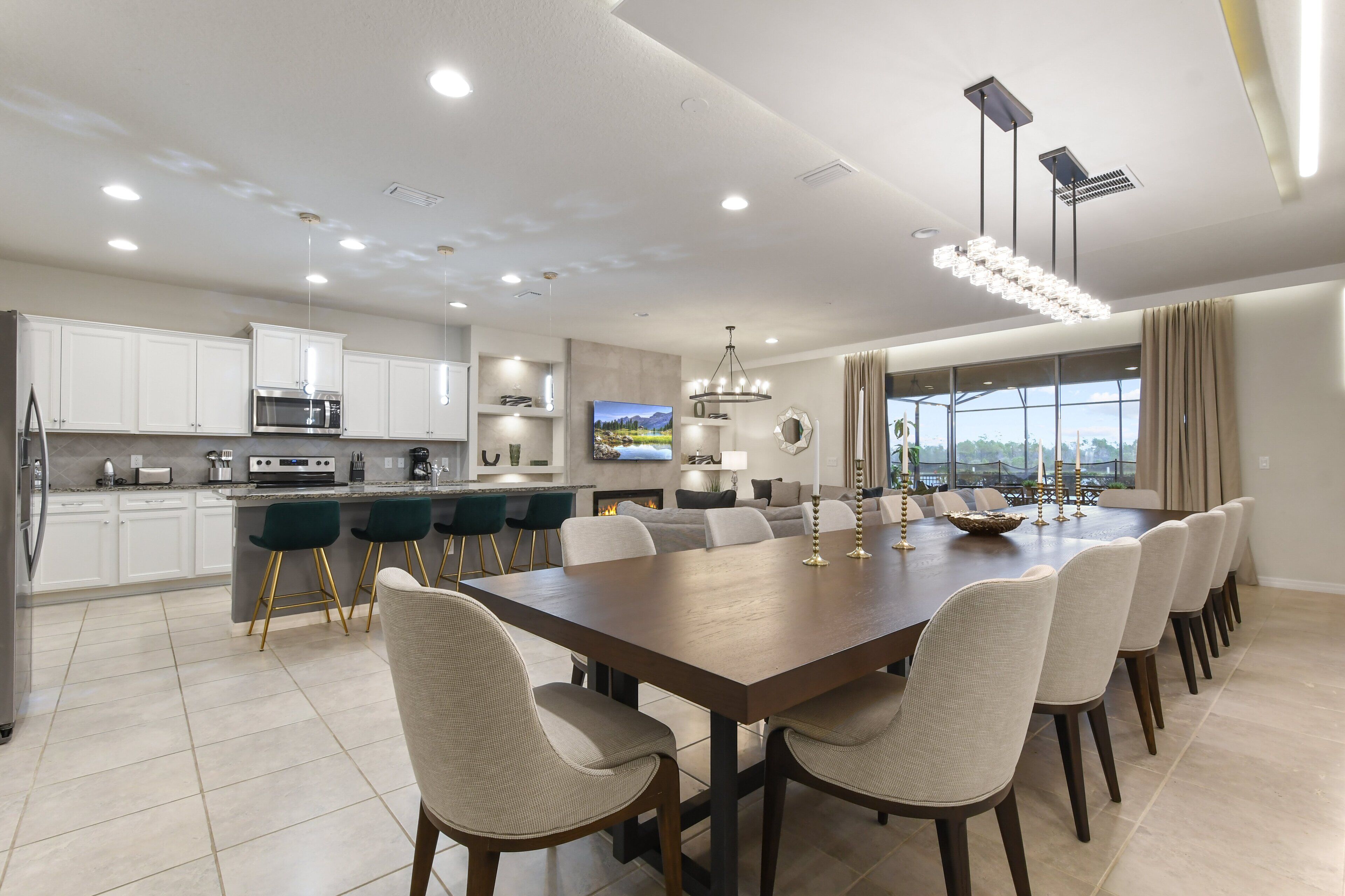 Una cocina moderna con armarios blancos, una isla grande y un comedor con una mesa larga y sillas.