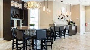 A modern kitchen with a central island, bar seating, pendant lighting, and decorative wall art. - 7BR Solterra Resort - Newly Renovated Home w Pool (Davenport)