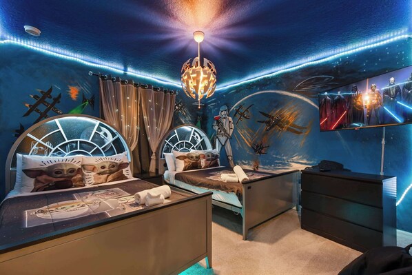 Quarto com duas camas, uma luminária no teto e um mural na parede.