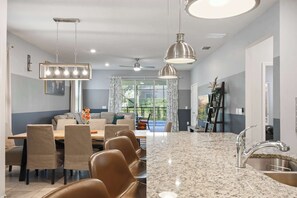 A modern kitchen with granite countertops, stainless steel appliances, and pendant lighting.