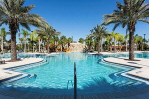 Uma piscina ampla e convidativa, cercada por palmeiras e espreguiçadeiras.