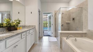 A modern bathroom with a walk-in shower, a large bathtub, and a vanity with a granite countertop. - 7BR Solterra Resort - Newly Renovated Home w Pool (Davenport)