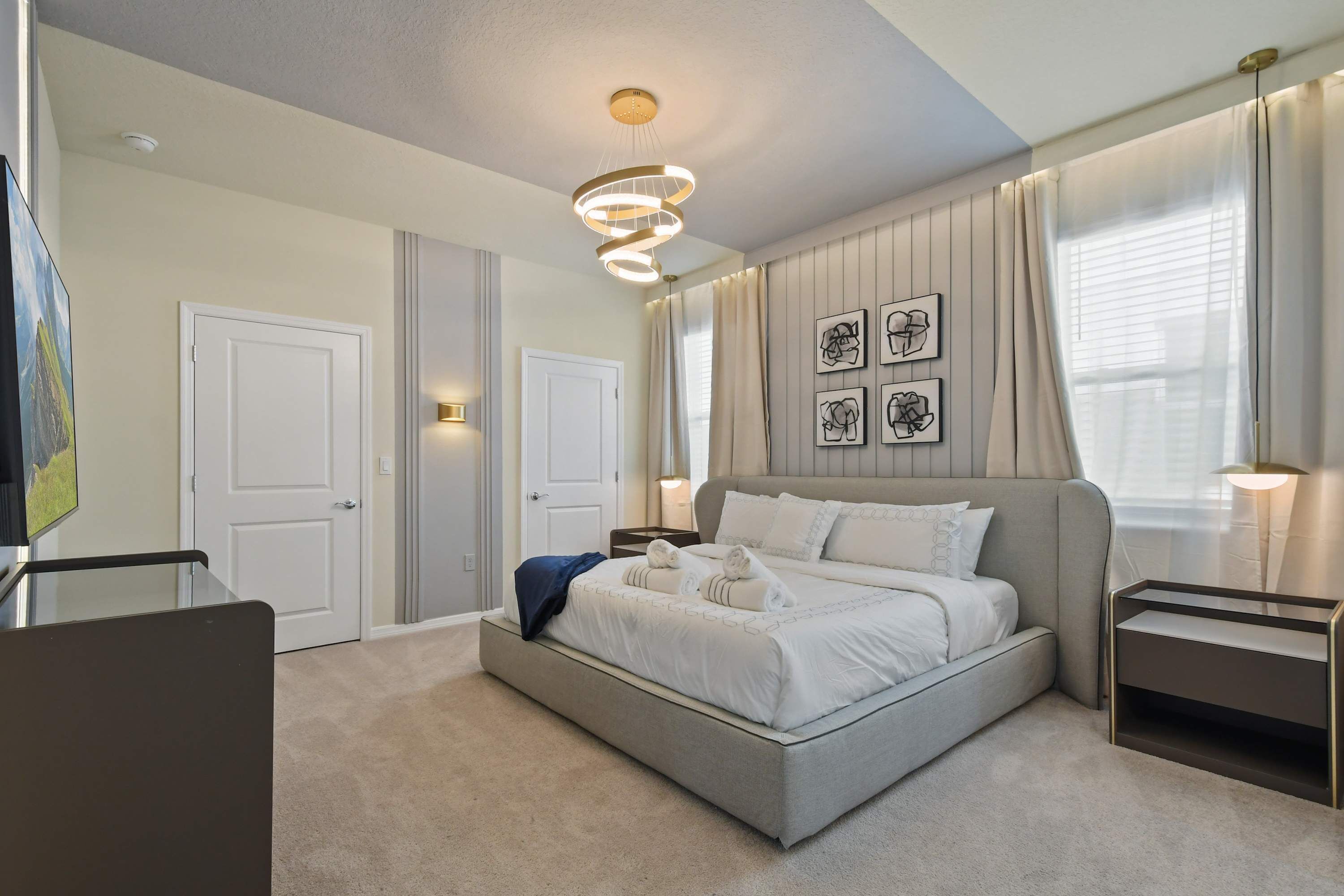 A modern bedroom with a large bed, bedside tables, and a ceiling light fixture.