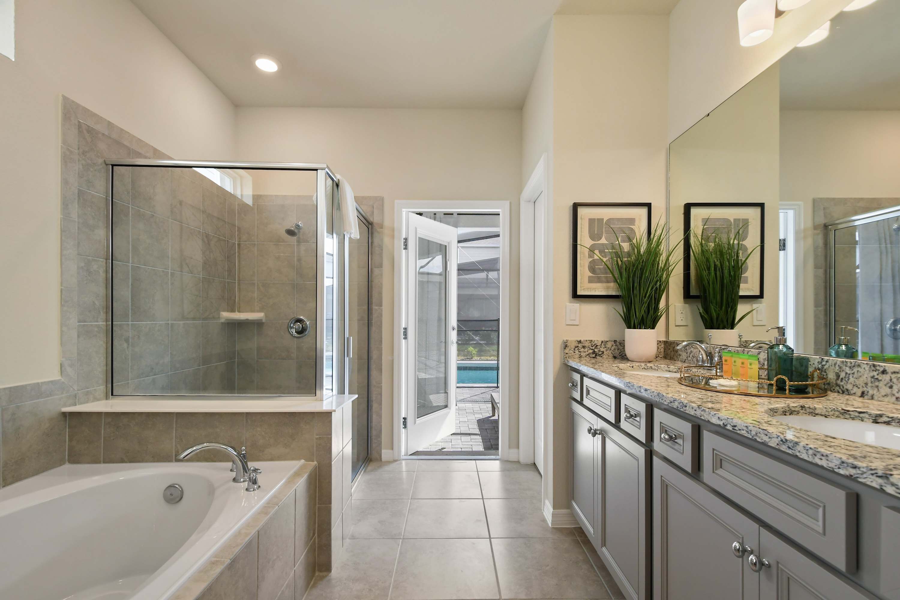 A modern bathroom with a glass-enclosed shower, a large bathtub, and a vanity with a sink and countertop.
