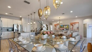 A modern kitchen with a glass dining table, stainless steel appliances, and decorative lighting. - Elegant Home With Pool & Spa, Close to Disney (Kissimmee)