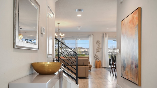 A modern interior with a staircase, a large mirror, a bowl on a console, a painting, and a view through the window. - Elegant Home With Pool & Spa, Close to Disney (Kissimmee)