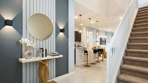 A modern interior with a staircase, a console table with a mirror, and pendant lighting. - Spacious Home w/ Private Pool, Near Disney (Davenport)