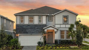 A two-story house with a garage, a stone facade, and a well-maintained garden. - Next to Clubhouse NEW Model Home Pool/spa/game/bbq (Davenport)