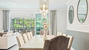Une salle à manger moderne avec une longue table, des sièges confortables et une grande fenêtre donnant sur un paysage verdoyant.