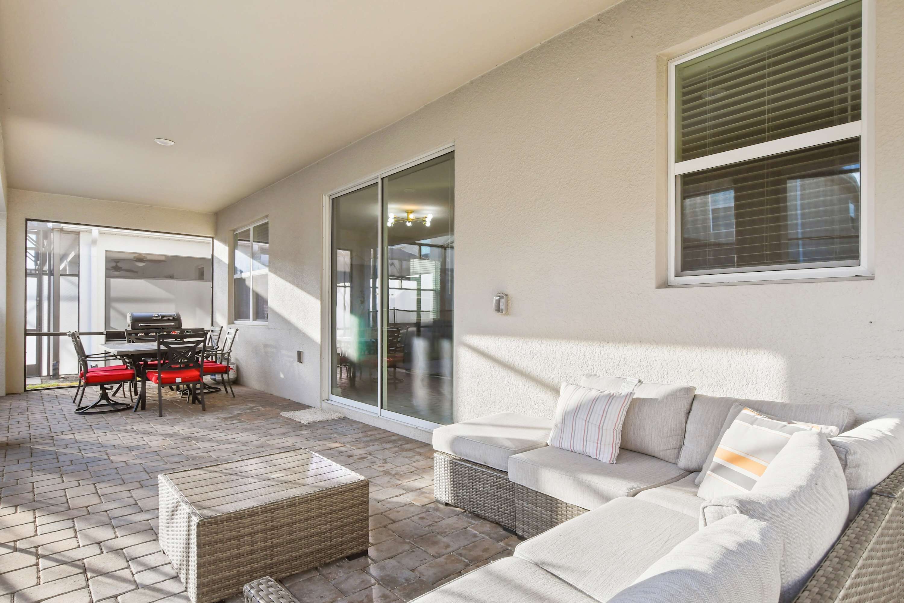 A covered patio area with a dining table and chairs, a sofa, and a wicker coffee table.