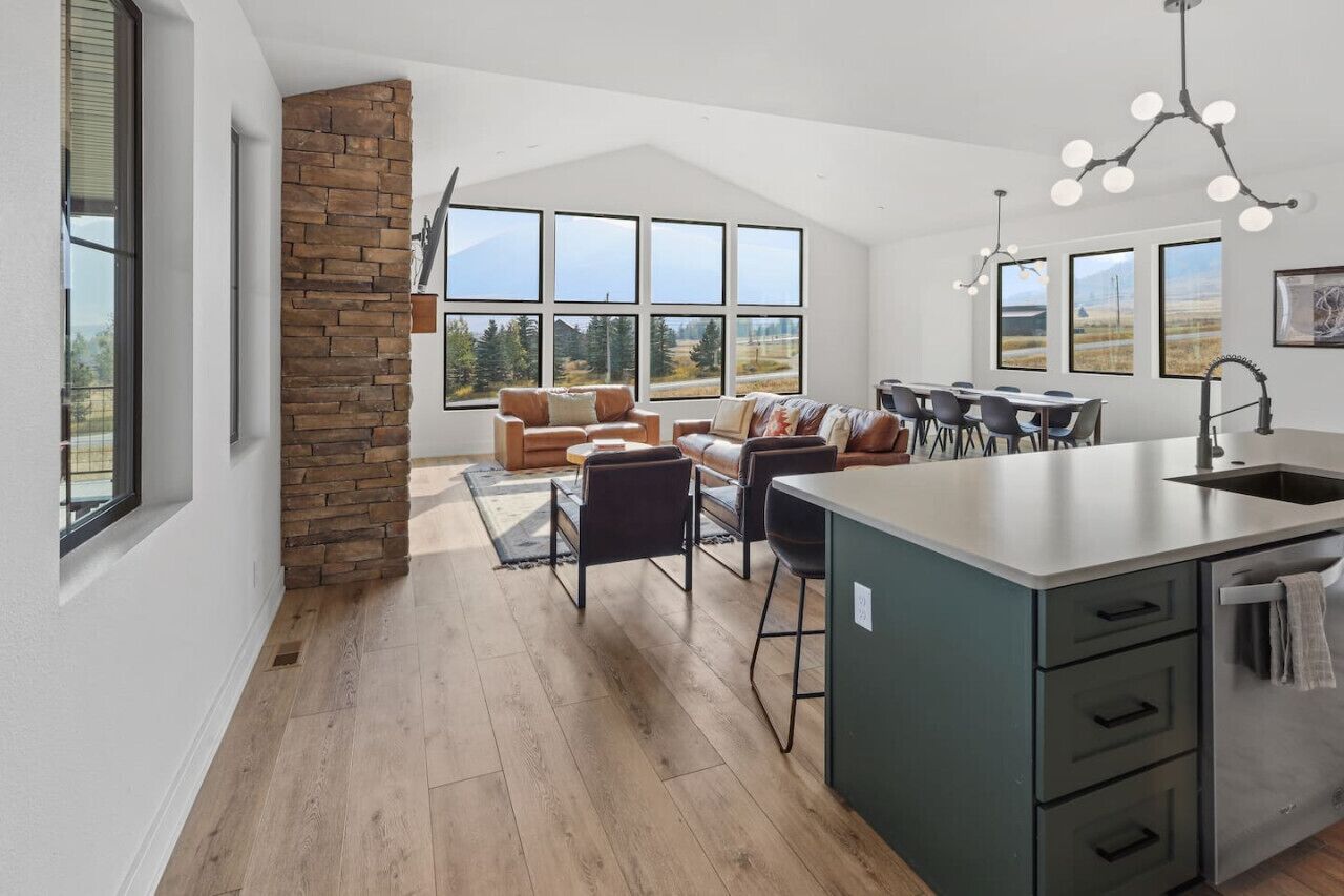 A modern kitchen with a stone accent wall, large windows, and a dining area with a view.