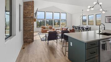 A modern kitchen with a stone accent wall, large windows, and a dining area with a view.